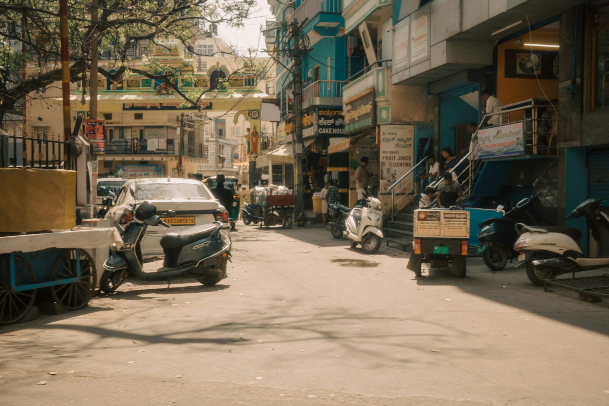 Sunny Bengaluru residential street with scooters and trees