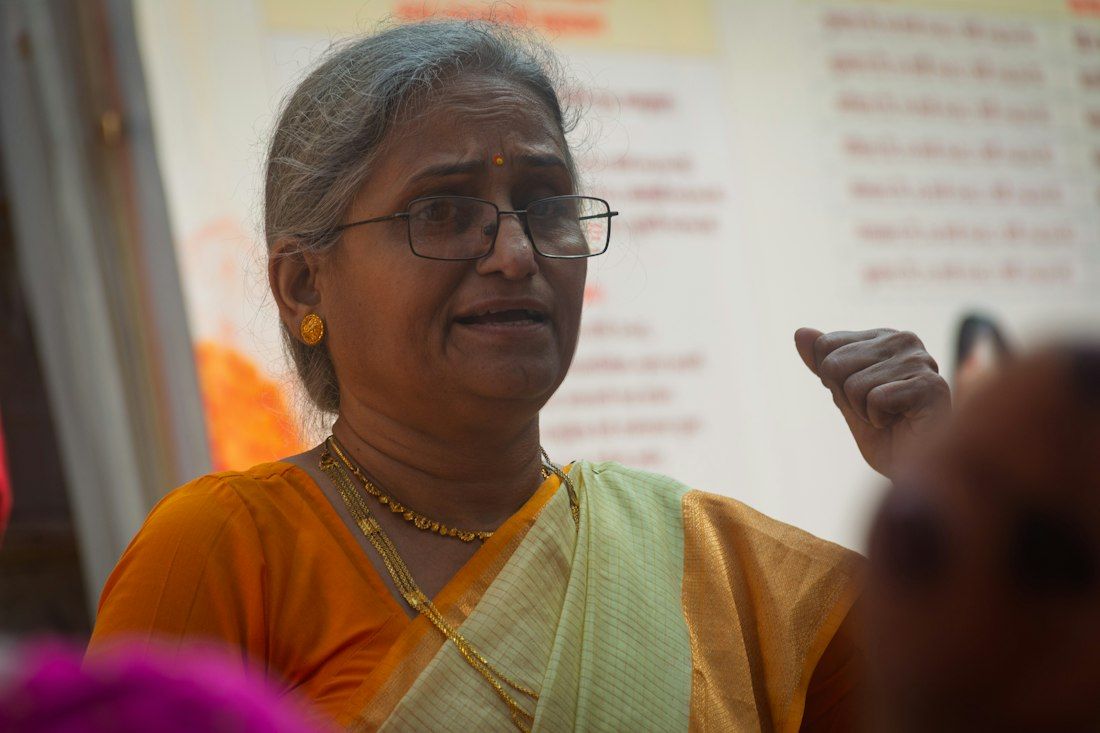 An elderly woman in glasses explaining something while talking with others