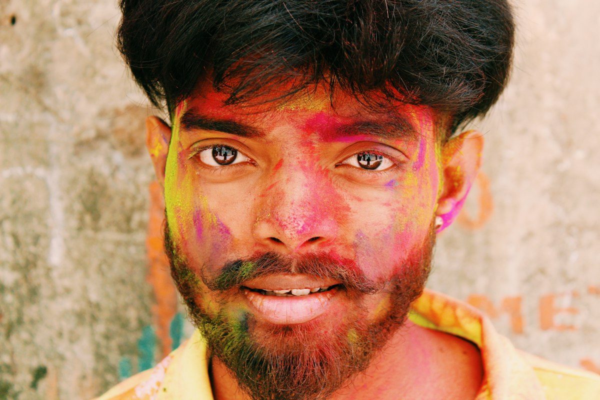 Young man smiling with festival colours on his face