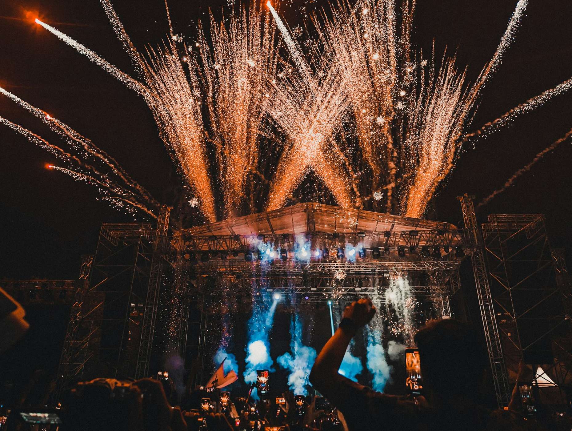 Concert stage lit up with sparklers and fireworks over a crowd
