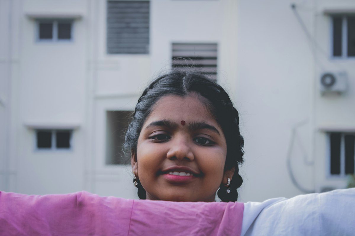Cheerful young woman in a pink top with her arms spread wide