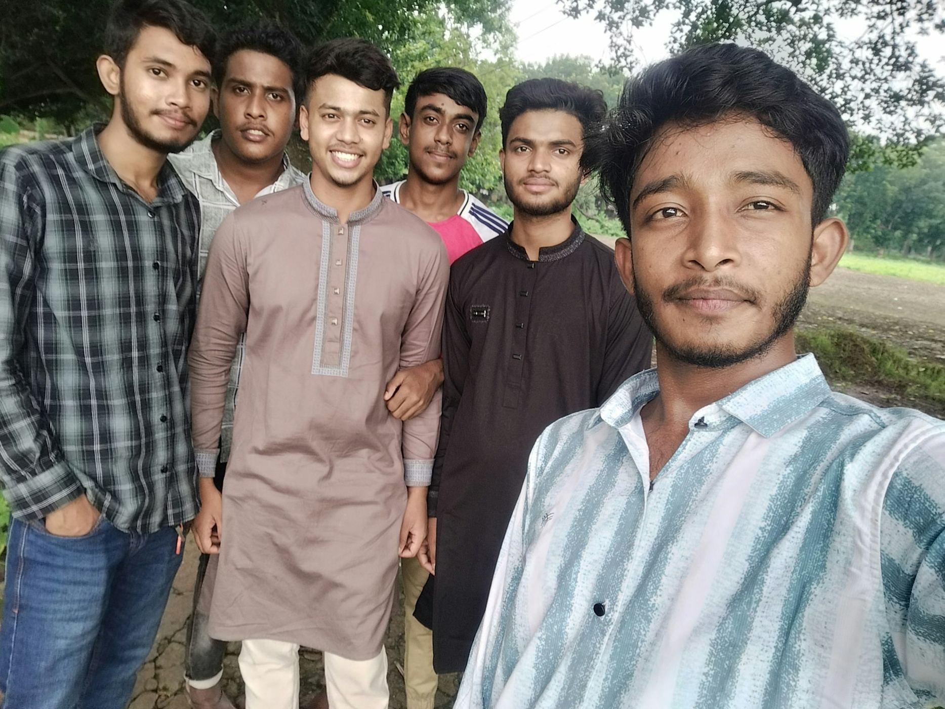 Six young friends taking a group selfie outdoors