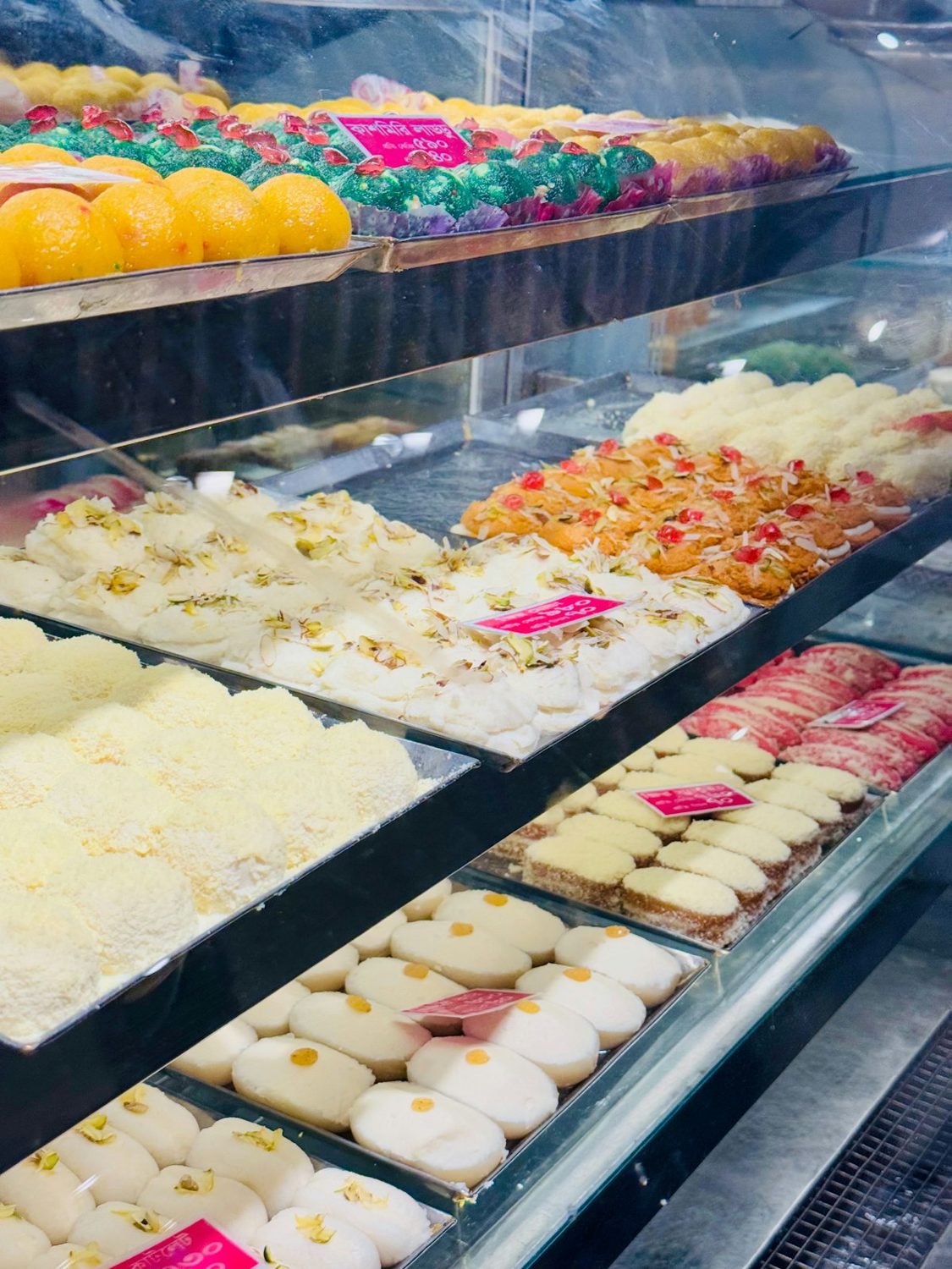 Sweet-shop display counter with trays of Indian sweets