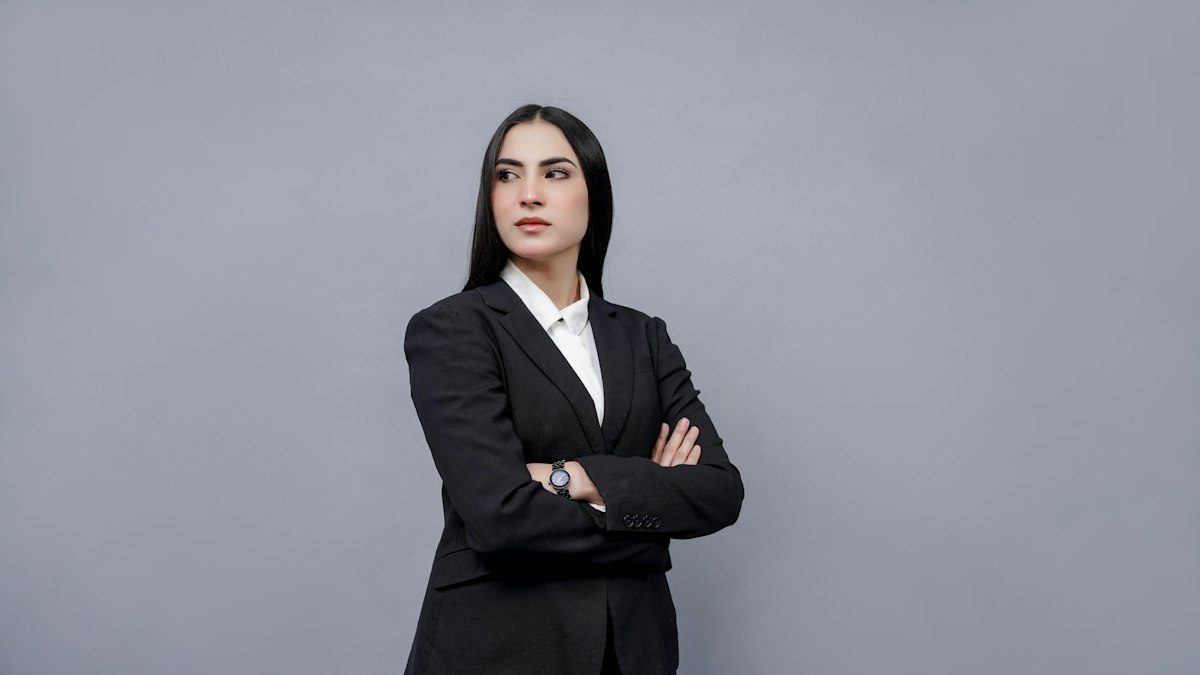 Confident woman in a black suit against a grey backdrop