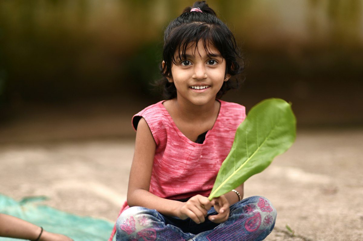 Smiling young girl holding a leaf outdoors