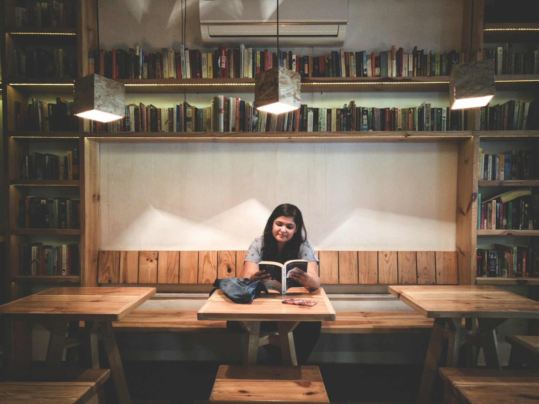 Young woman reading in a wood-panelled library café
