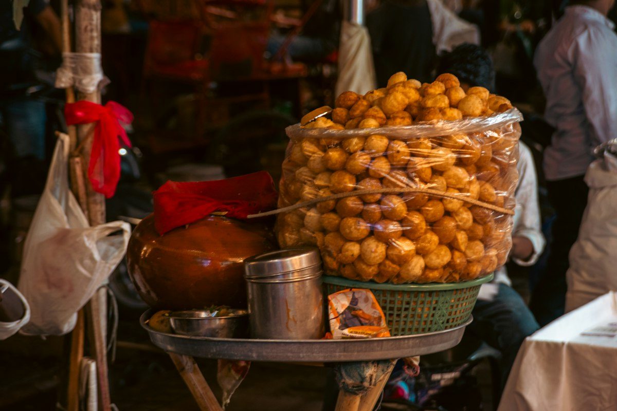 Street vendor with a large jar of fried snacks