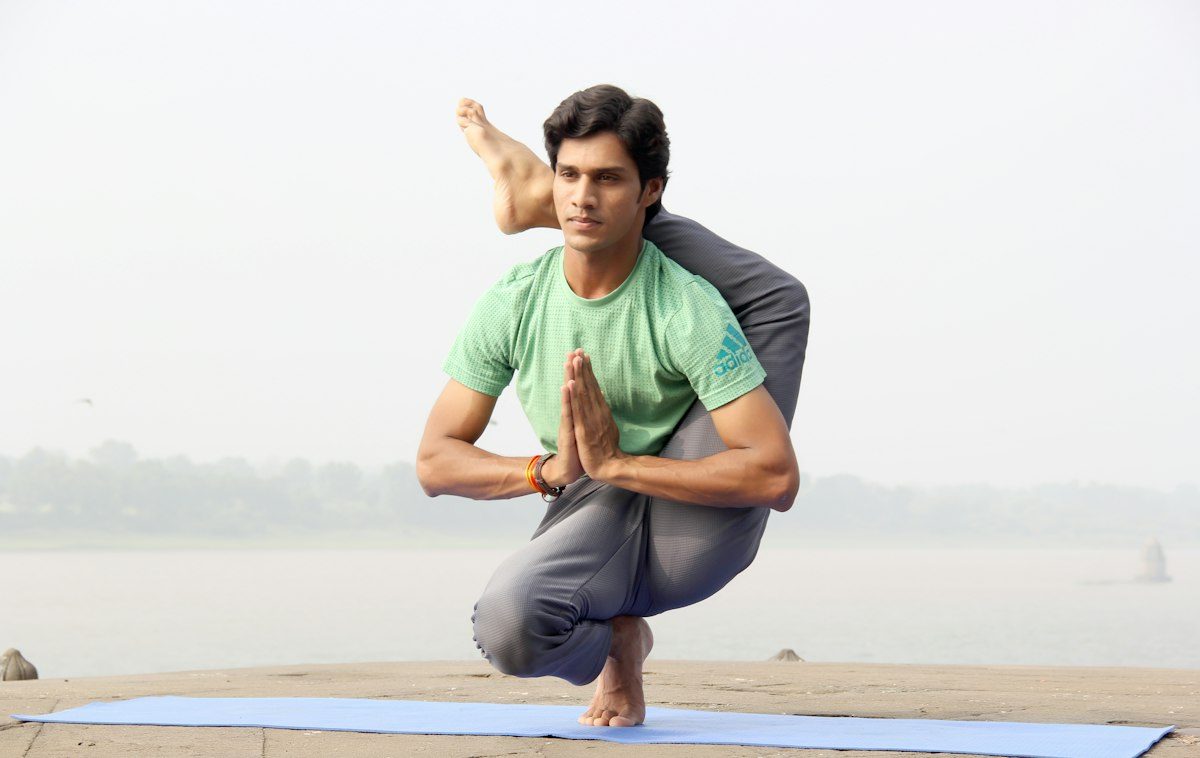 Man holding a yoga balance pose by the water