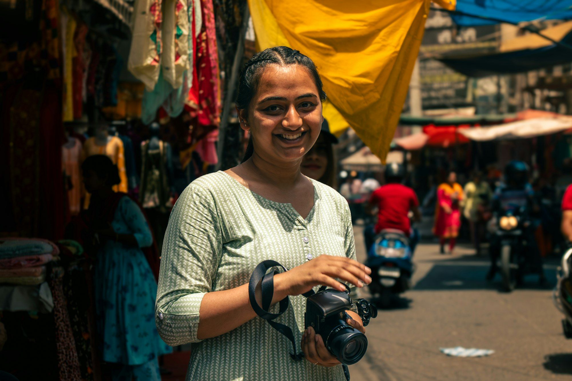 A smiling young woman with a camera in a colourful Bengaluru market