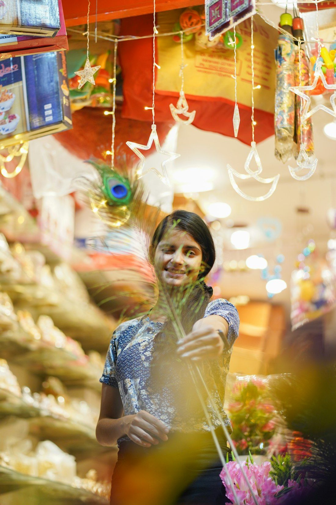 A young woman smiling in a festive shop lit with fairy lights